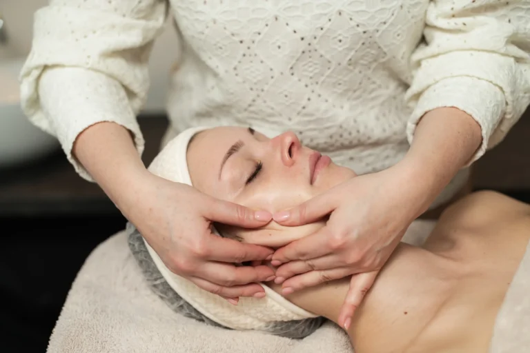 Schoonheidsspecialist met beide handen op het gezicht van een klant tijdens een bindweefselmassage bij Dessa Skin